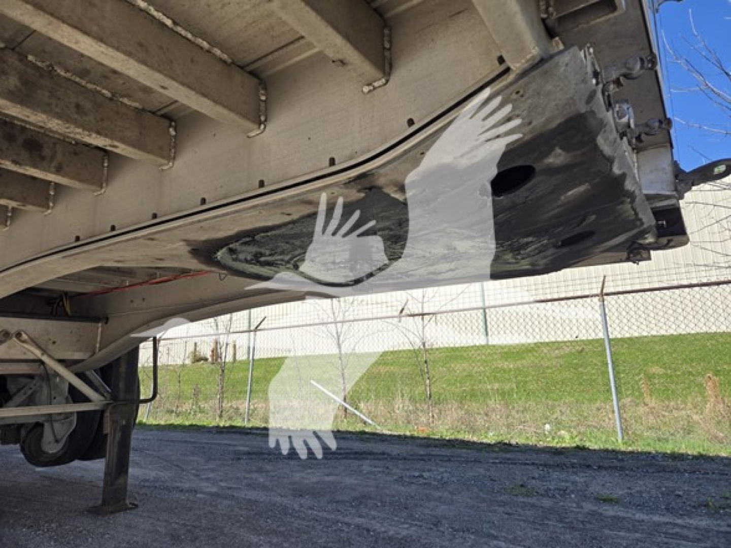 Trailer underside showing aluminum flatbed with a painted white bird logo, side rails, and support structure visible.