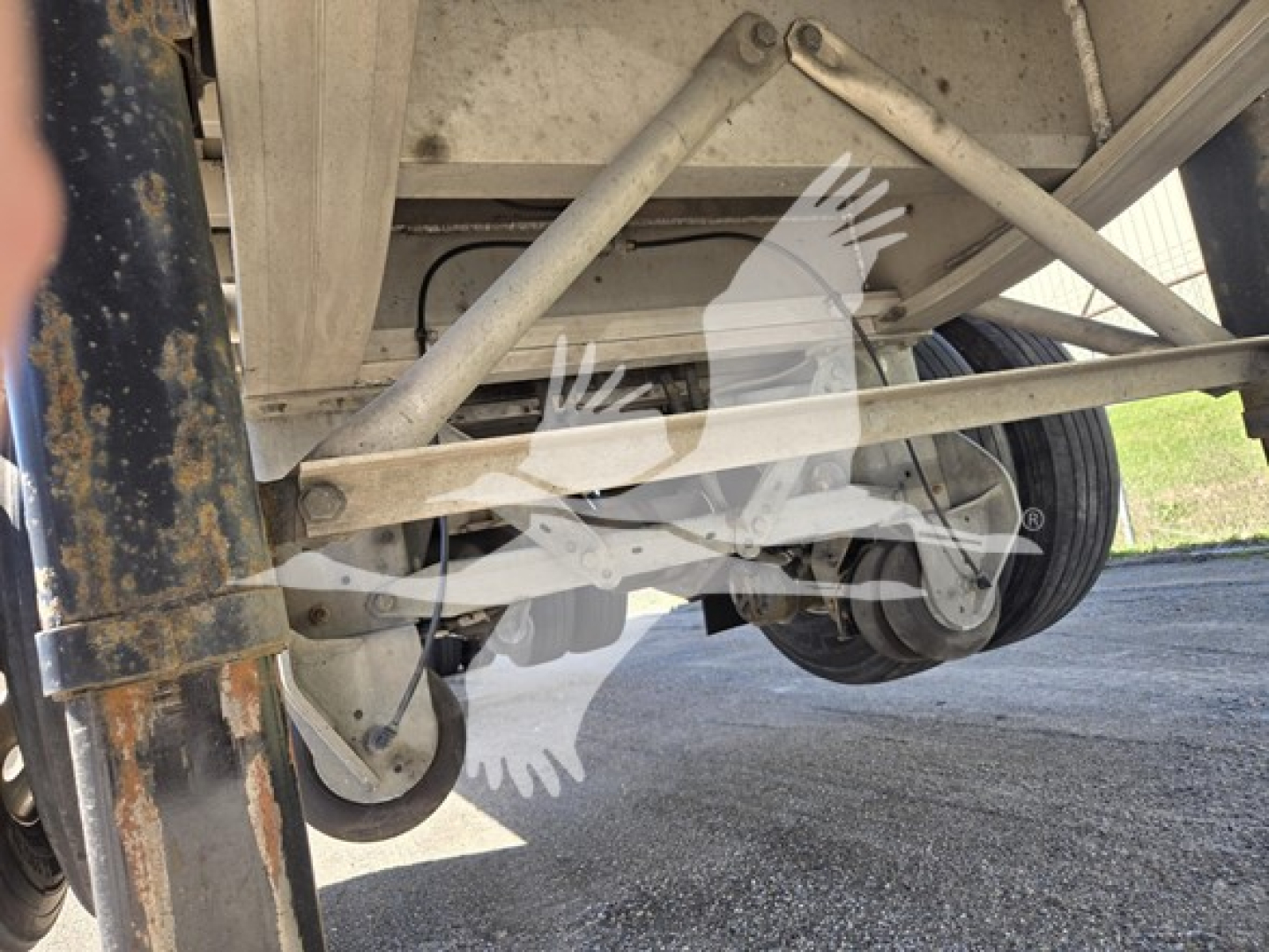Trailer undercarriage showing suspension frame and axle with wheel hub and leaf springs in a Mac Aluminum flatbed.