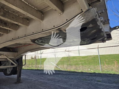 Trailer underside showing aluminum flatbed with a painted white bird logo, side rails, and support structure visible.