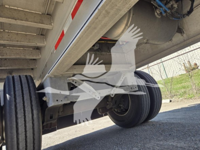 Mac aluminum flatbed trailer underside showing tandem axle and suspension with exposed wheel and frame components.