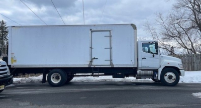 Truck side view showing box cargo body with rear door hinge and steps on a Hino 268 box truck.
