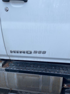 Truck side showing HINO 268 emblem near lower door with perforated metal step rail.