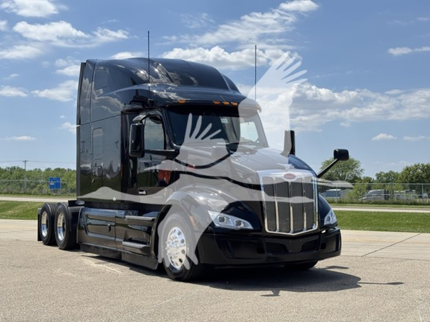 Peterbilt 579 tractor used in service, black aerodynamic sleeper with chrome grille, three axles, sitting on asphalt under blue sky.
