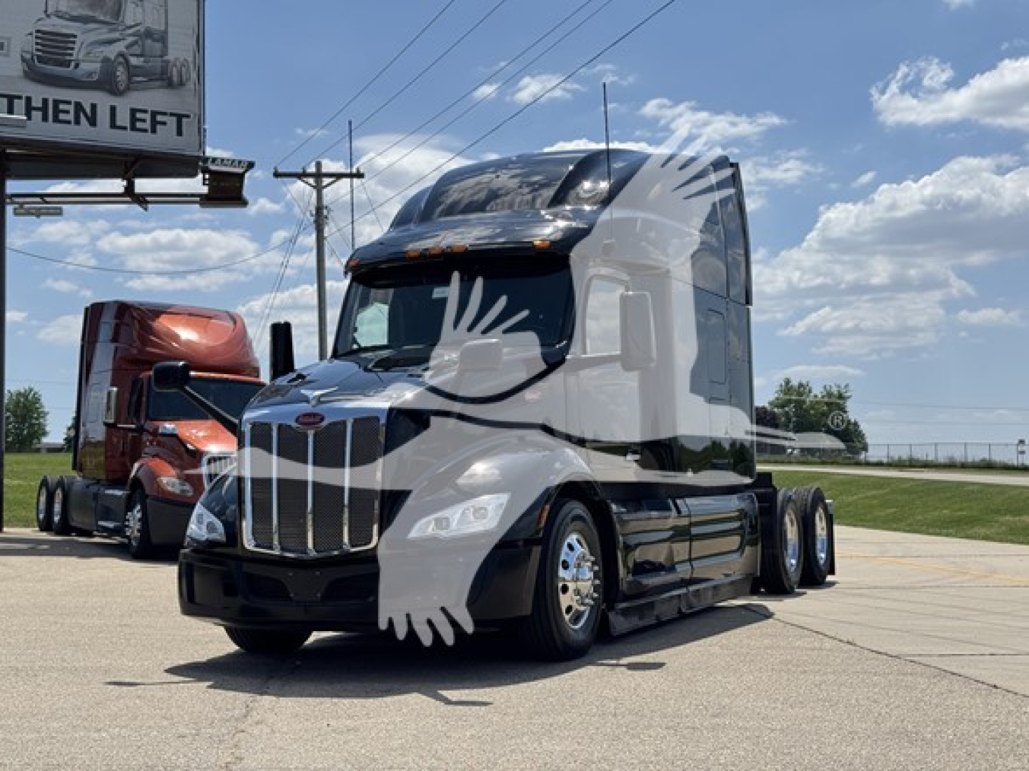 Peterbilt 579 semi-truck in a dealership lot, white and black, front view with chrome grille and sleeper cab.