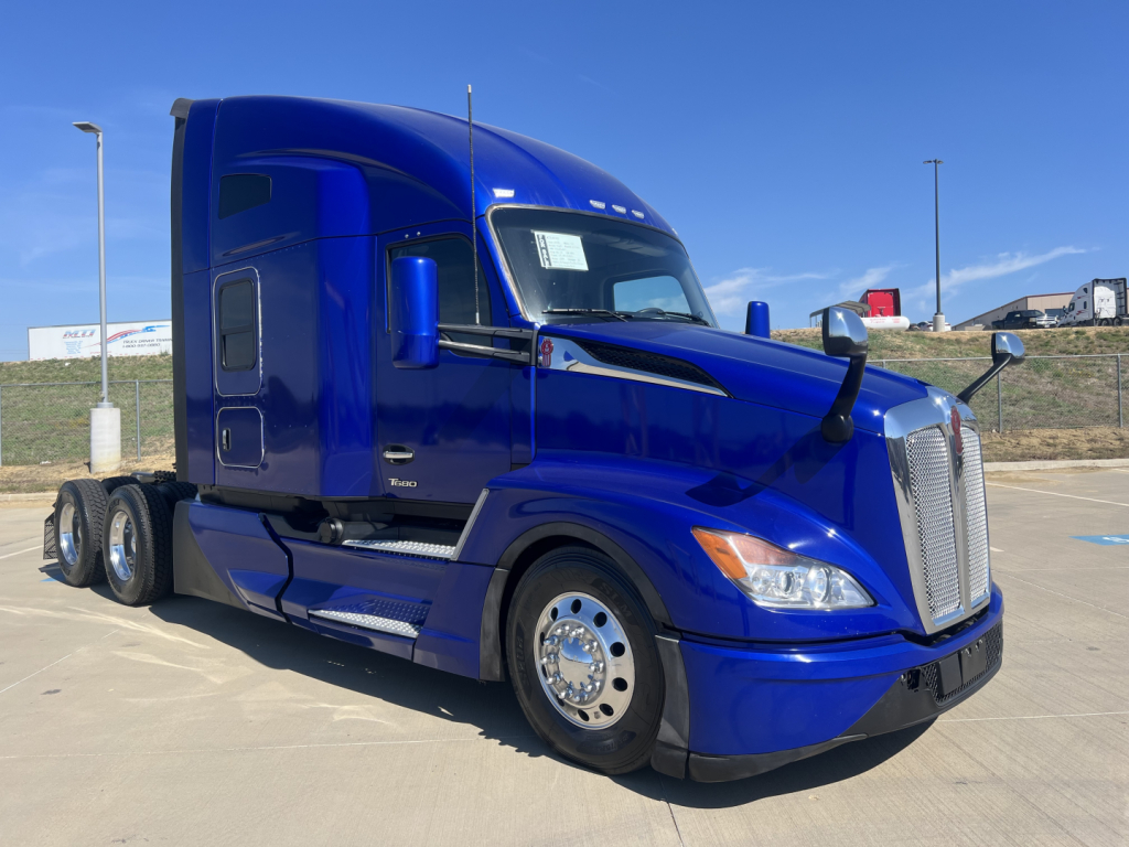 Kenworth T680 conventional sleeper truck in blue, side view with chrome wheels and dual rear axles.