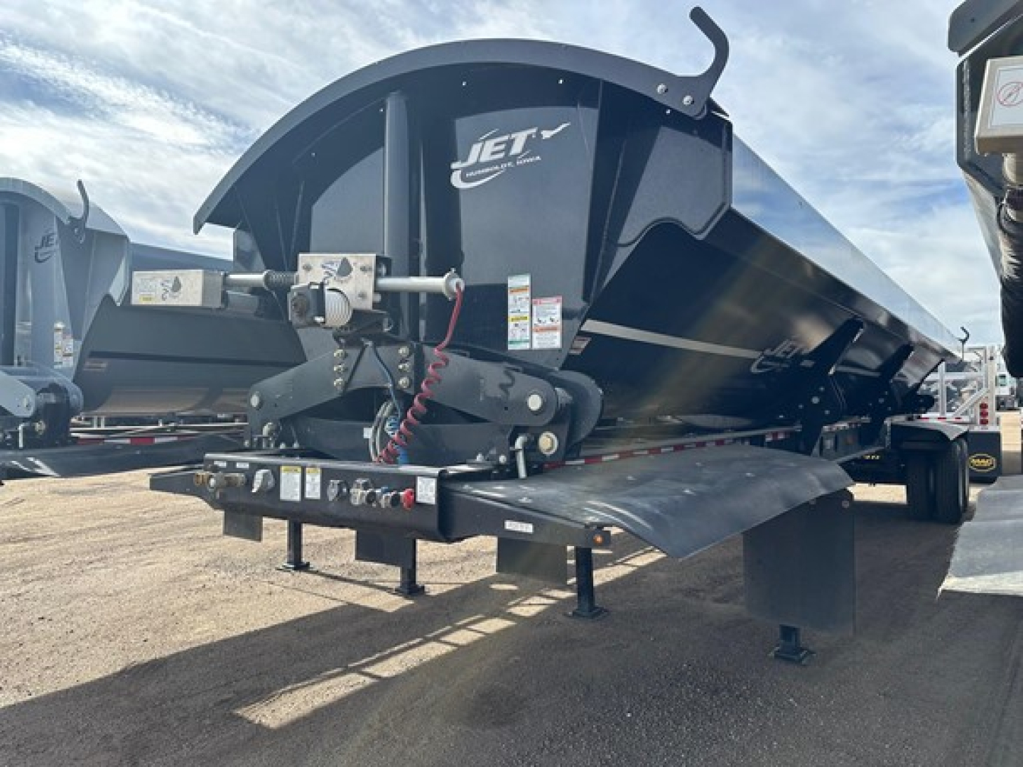 Jet Jet Air Ride Side Dump trailer showing hydraulic system, pivoting hopper, and rear bumper with safety chains and lights.