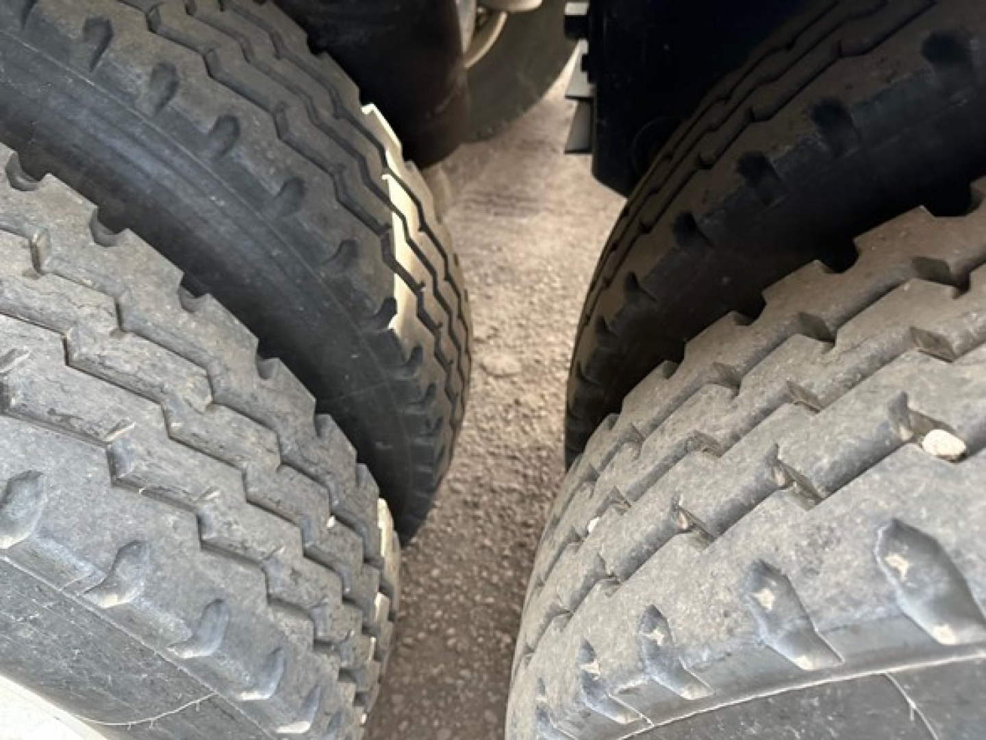 Dual-axle trailer wheels view showing treaded tires and suspension near the axle; no-scale text visible.