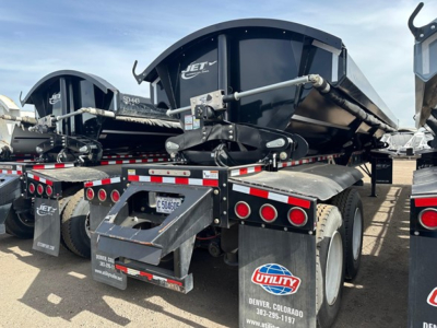 Jet equipment trailer showing side-dump hopper with hydraulic lift and dual rear taillights, back view including mudflaps and license plate area; branding reads Jet.
