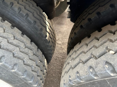 Dual-axle trailer wheels view showing treaded tires and suspension near the axle; no-scale text visible.