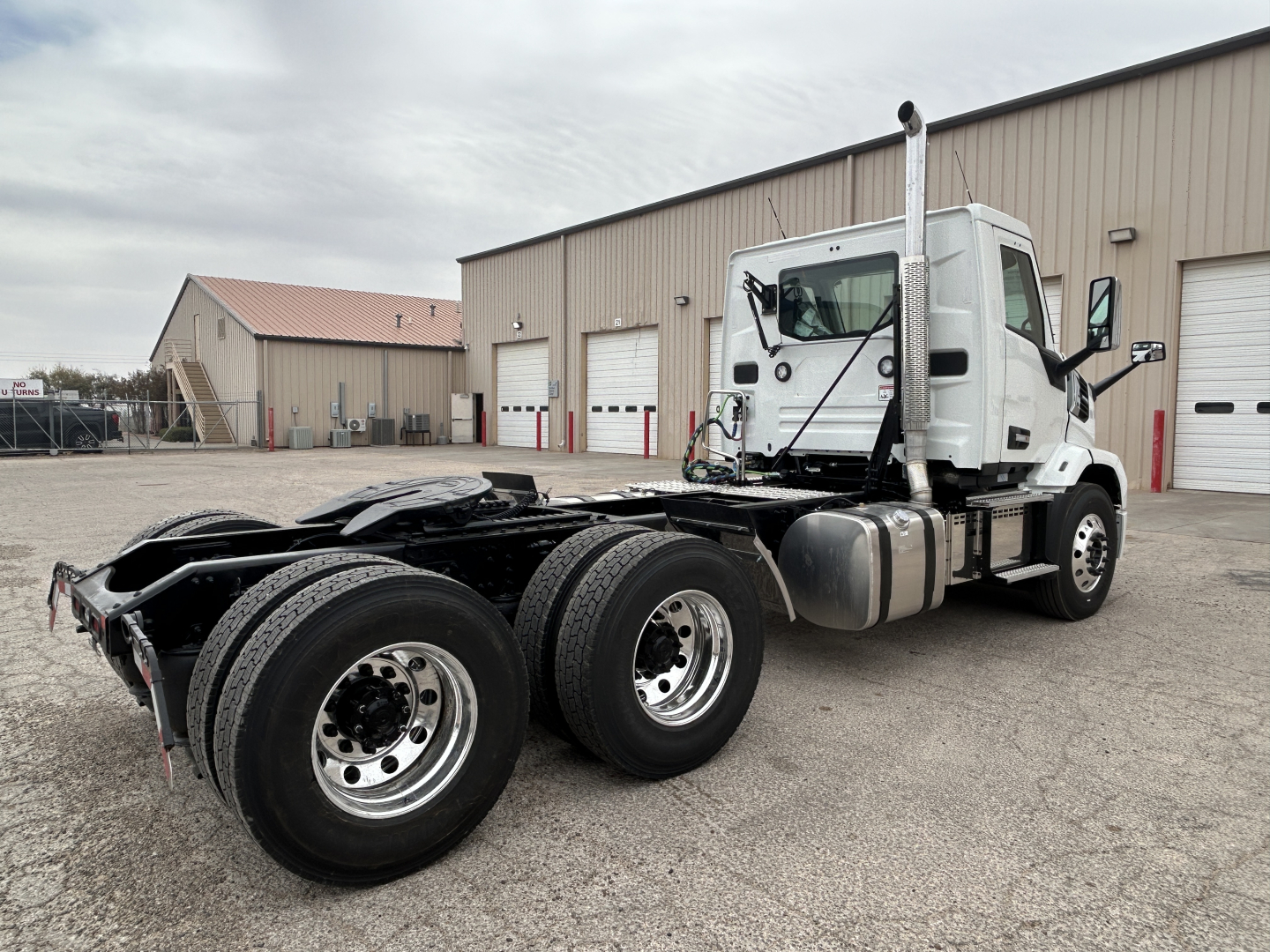 Mack AN64T conventional daycab tractor rear dual-axle chassis and cab view, white exterior, fuel tanks, exhaust stack visible.