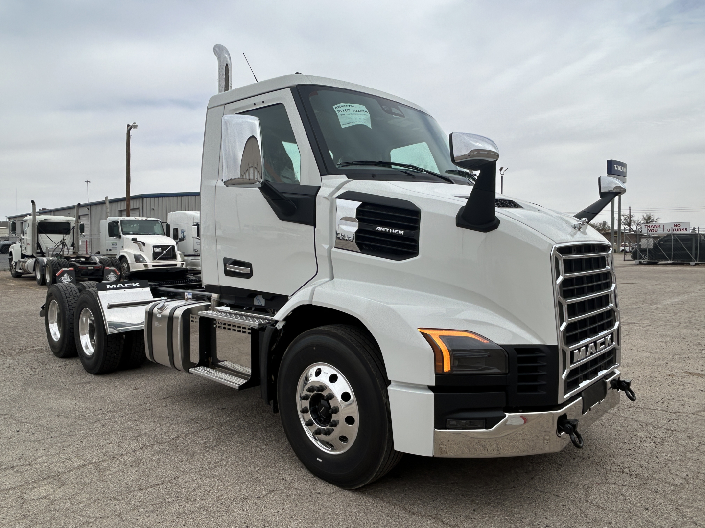 Truck cab in a lot showing Mack AN64T branding on the grille and side vent, with chrome bumper and dual fuel tanks.