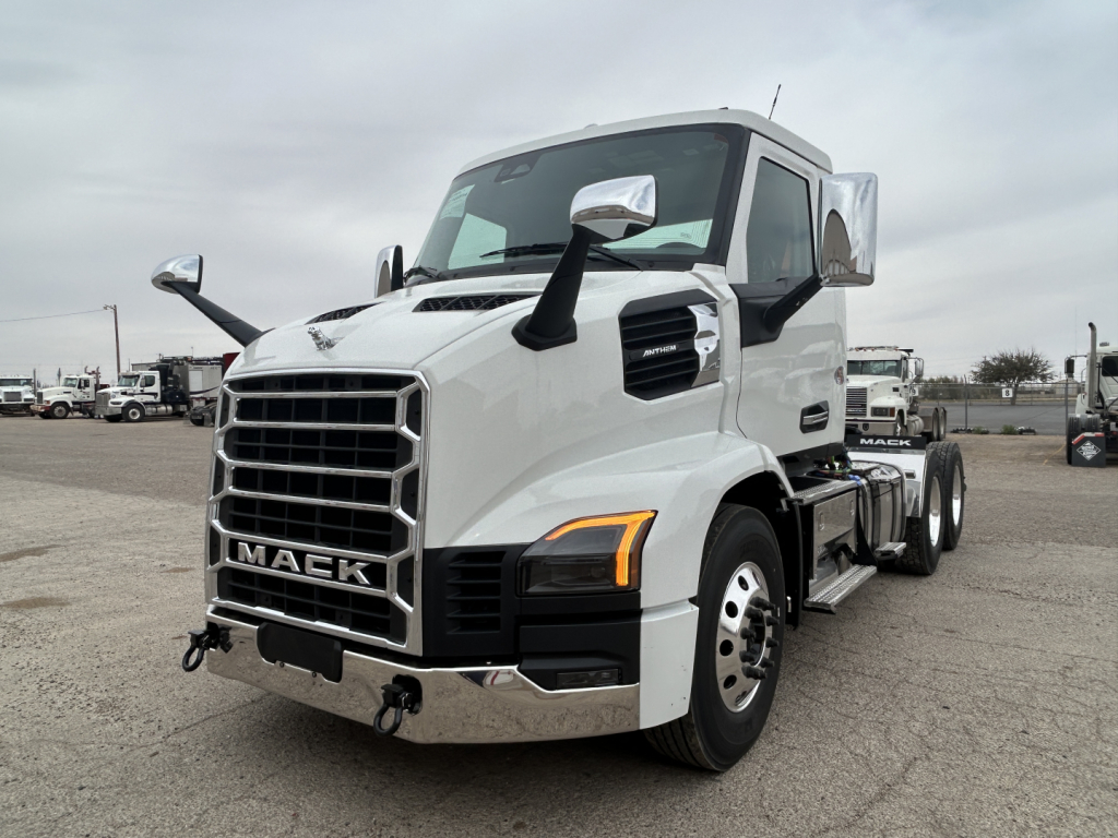 Truck front-left view of a white 2027 Mack AN64T conventional daycab with large grille, dual side mirrors, and amber turn signals.