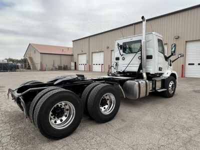 Mack AN64T conventional daycab tractor rear dual-axle chassis and cab view, white exterior, fuel tanks, exhaust stack visible.