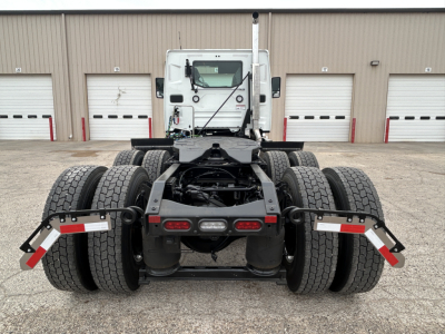 Truck rear view showing tandem axle configuration on a new Mack AN64T cab chassis with multiple dual rear wheels and black chassis components.