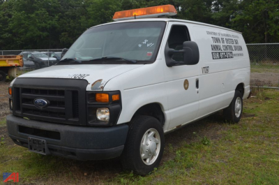 Ford Econoline cargo van in-service with orange light bar and company signage on side, front grille and headlights visible.