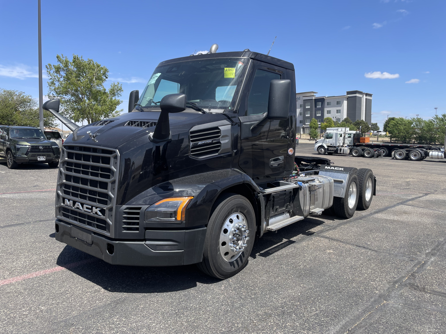 Mack AN64T conventional daycab truck in a parking lot, front three-quarter view showing black cab, grille with MACK badge, large headlights, and dual rear axles.