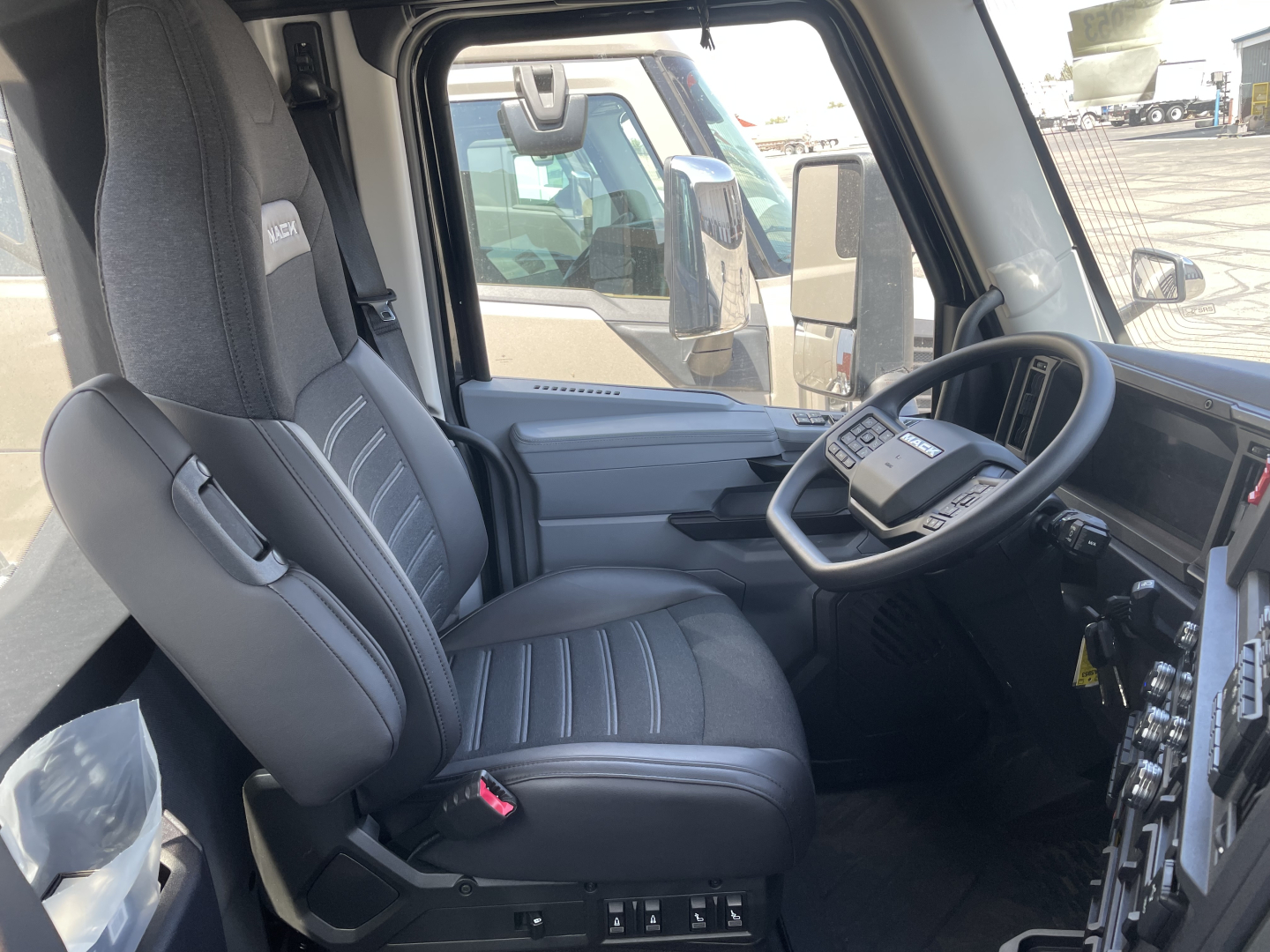 Seat and steering wheel area of a Mack AN64T cab showing driver seat, dashboard, and interior controls in a new conventional daycab.