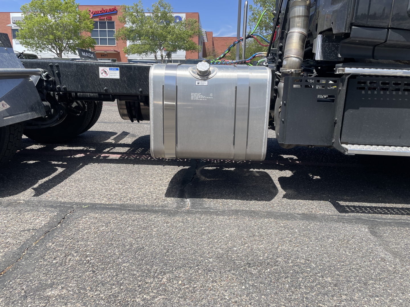 Tank fuel/auxiliary reservoir mounted under the Mack AN64T  cab chassis showing metal cap and mounting straps with surrounding frame.