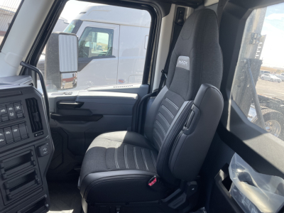 Mack AN64T truck interior showing driver and passenger seats with gray fabric, dashboard, and door panel viewed from cabin angle.
