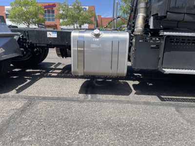 Tank fuel/auxiliary reservoir mounted under the Mack AN64T  cab chassis showing metal cap and mounting straps with surrounding frame.
