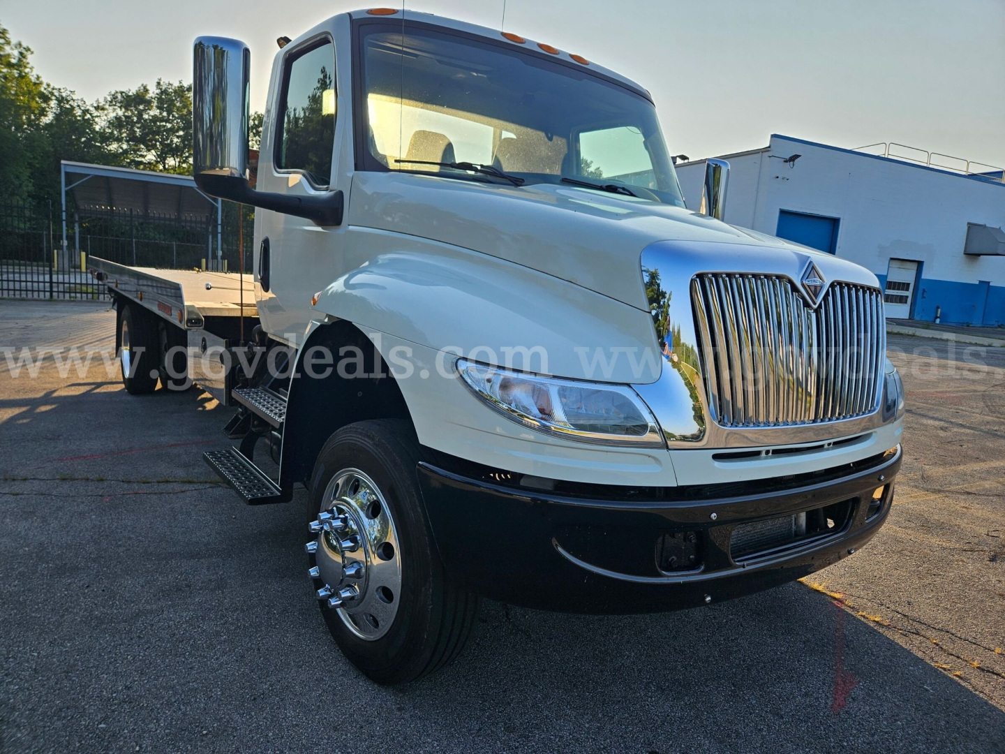 International MV607 tow truck front-left view showing chrome grille, dual rear wheels, and flatbed; VIN 1FVAG3DX4JHJL3327 visible; stock 3956-925.