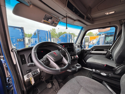 Kenworth T680 Next Gen cab interior showing steering wheel, dashboard, and driver seat from passenger side.