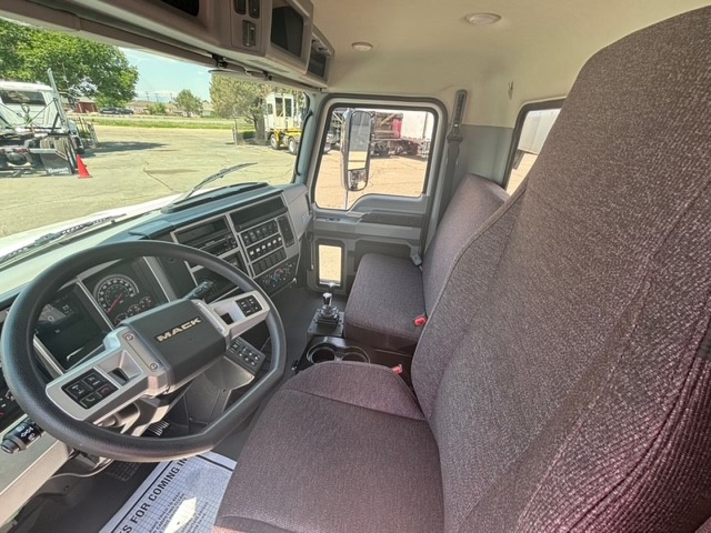 Interior of a new Mack MD7 hooklift truck showing steering wheel, dashboard, and front seats.