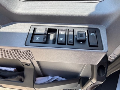 Cab interior controls panel with multiple switches and a cup holder on the right side; part of a Mack MD7 truck dashboard.