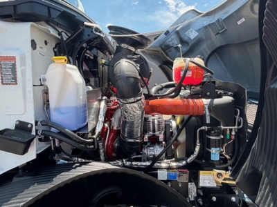 Mack MD7 engine bay view with coolant reservoir, hoses, and intake components visible