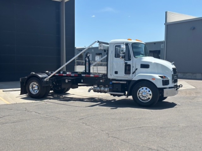 Mack MD7 hooklift truck side view showing cab, chassis, and hooklift arm assembly with white paint and chrome wheels.