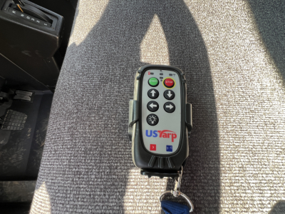 Controller remote with USfarp logo and green power button; dash area and pedals visible in background.