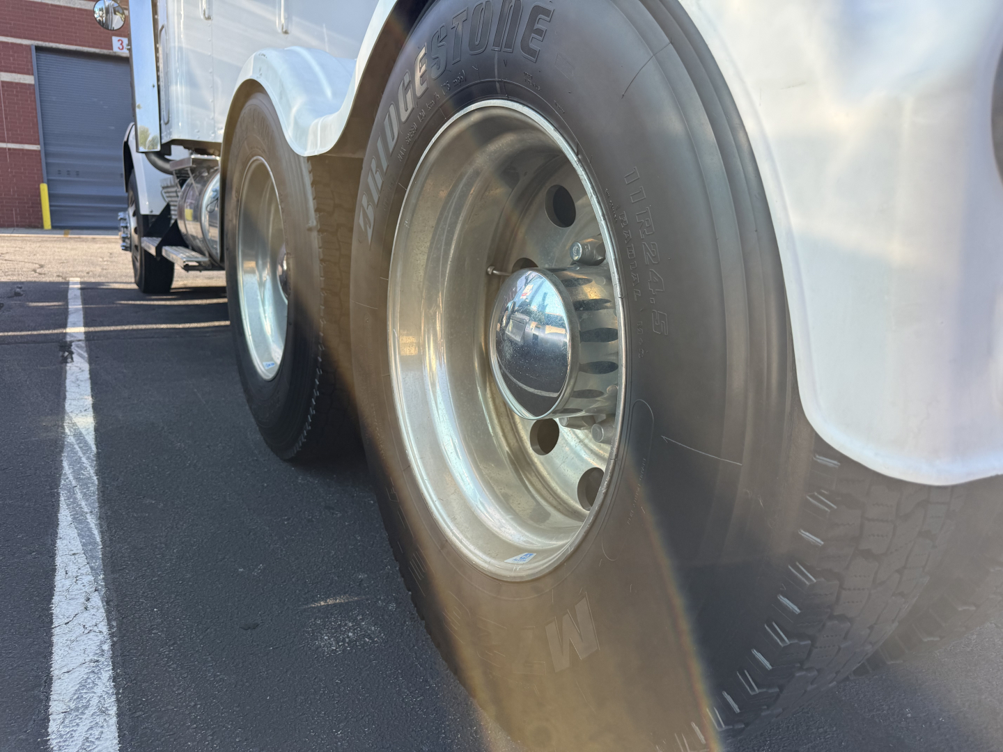 Kenworth T800 truck wheel/view showing front dual tires and chrome hubcap, part of a sleeper-conventional truck.