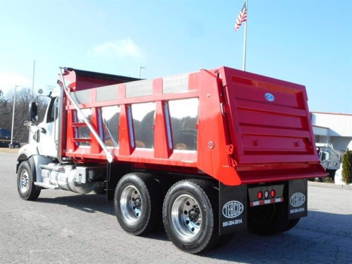 Western Star 47X dump truck in red with white cab, side view showing dump bed and dual rear axles.