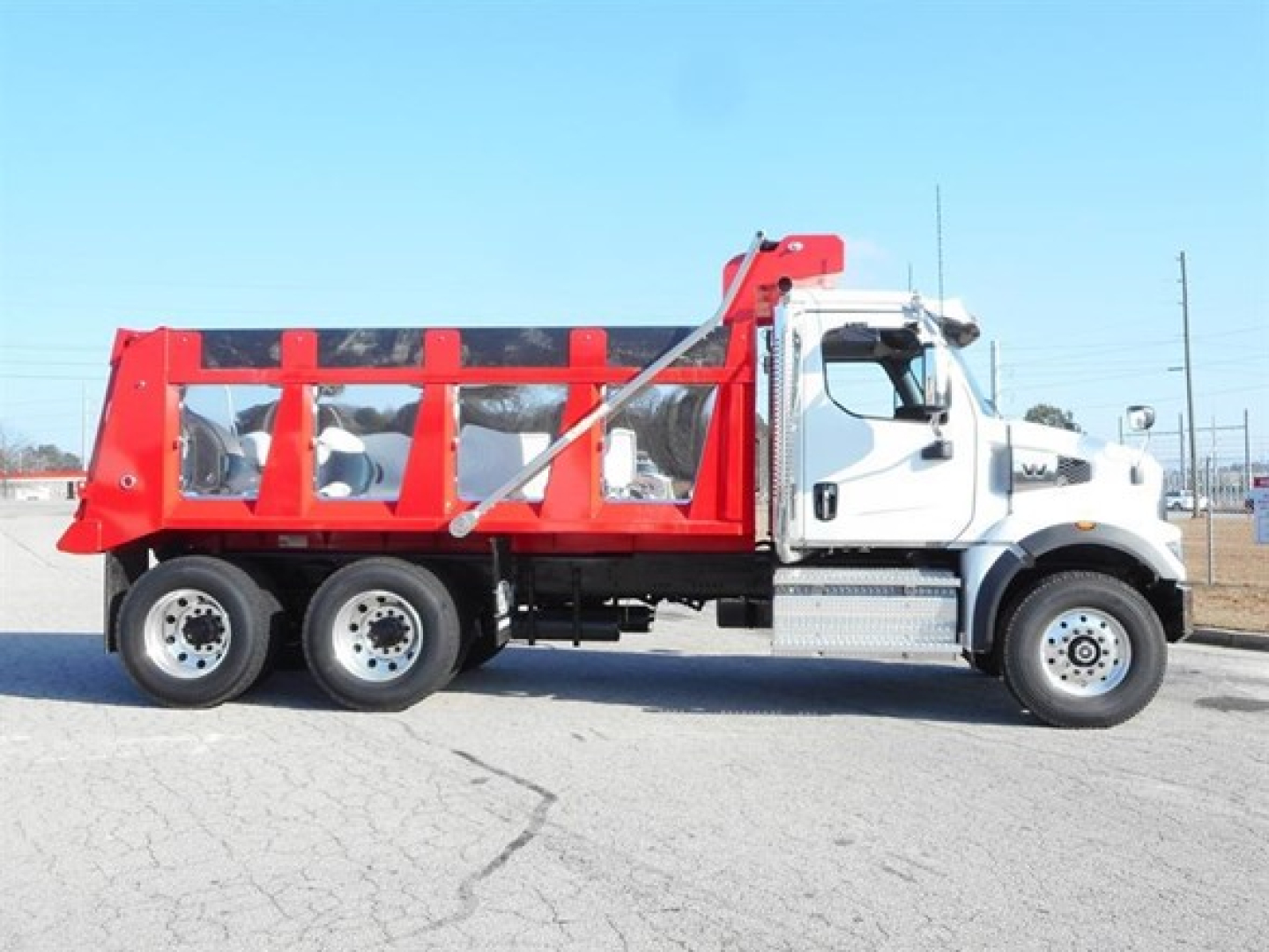 Truck side view showing a white cab and red dump body on a Western Star 47X dump truck.