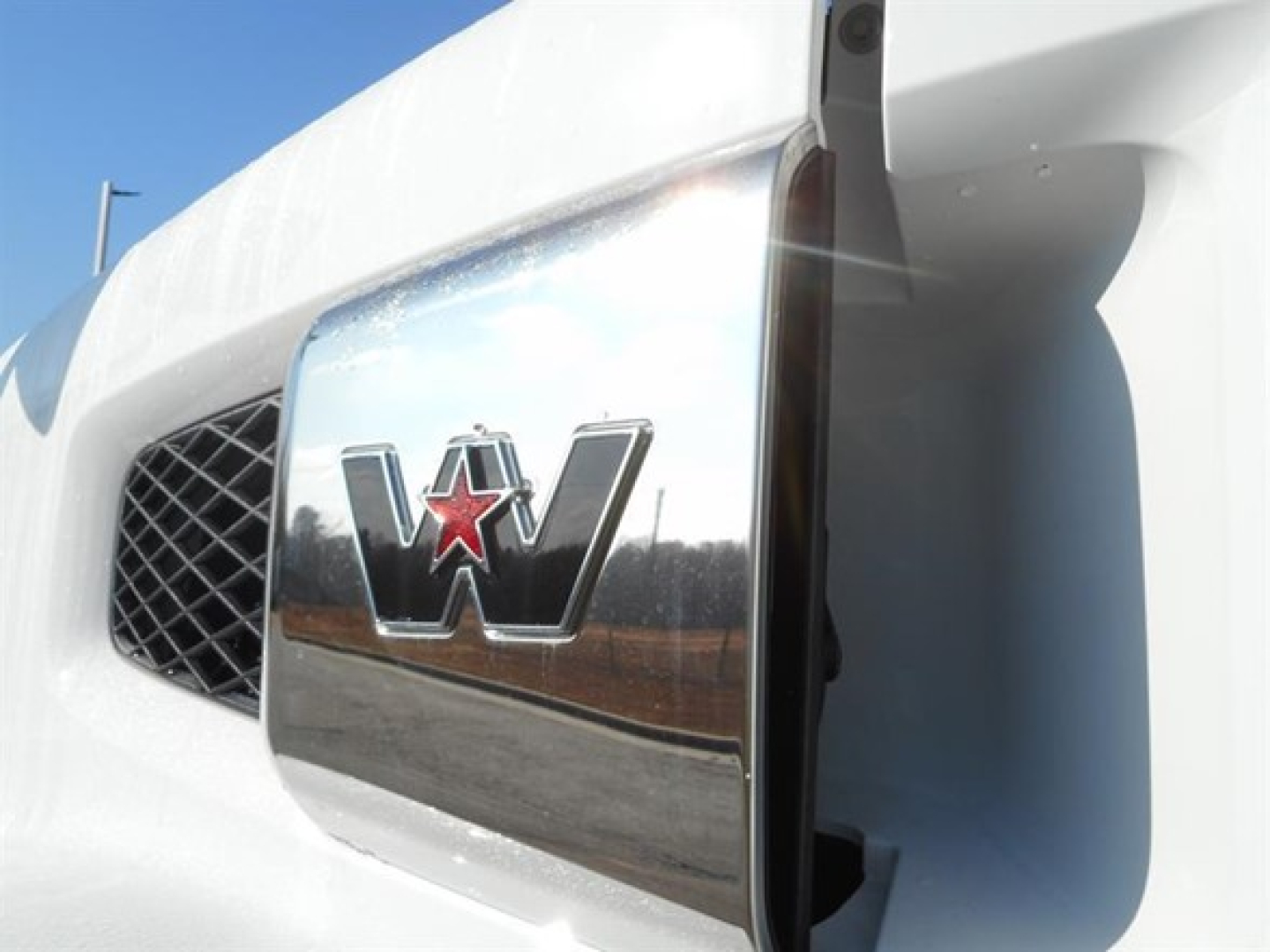 Western Star logo on the truck hood chrome emblem close-up showing front grille and headlight area.