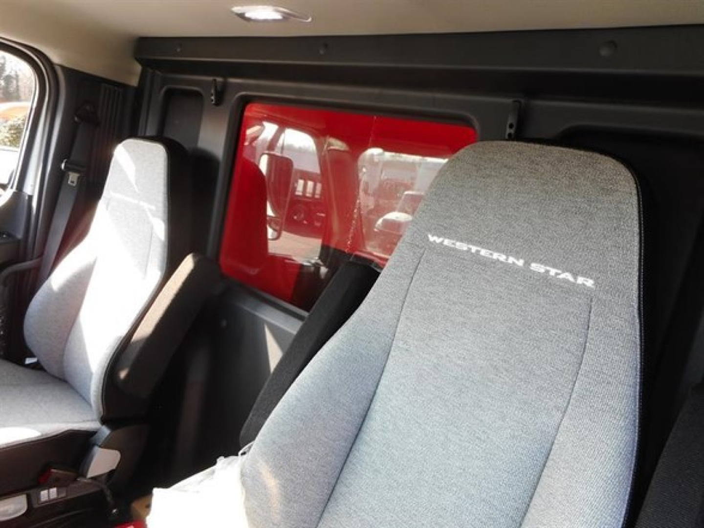 Western Star 47X interior seats with 'WESTERN STAR' logo visible on seatback and red exterior window panel in background.