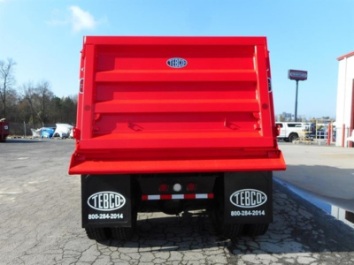 Dump truck bed back view showing bright red cargo box and dual TEBCO mud flaps with contact numbers.