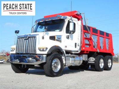 Western Star 47X dump truck in showroom angle showing white cab and red dump body with Peach State Truck Centers logo.