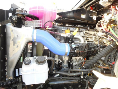 Western Star 47X engine bay showing coolant reservoir, blue intercooler hose, and various hoses and components in view.