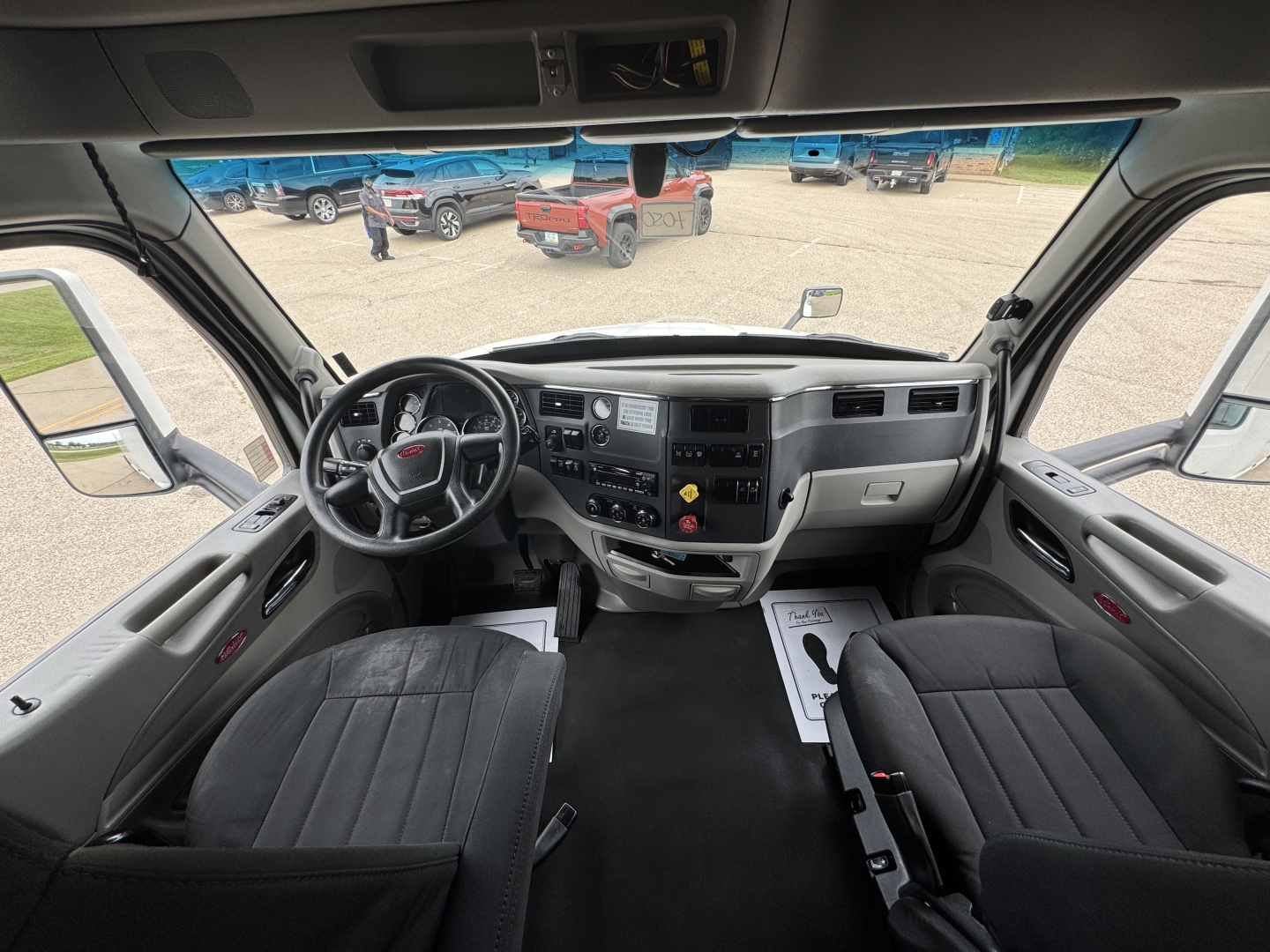 Cab interior of a 2022 Peterbilt 579 conventional sleeper showing dashboard with steering wheel, gauges, center console, and two front seats.