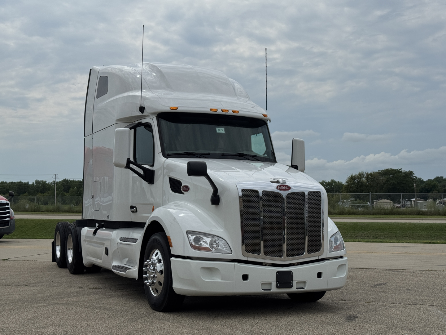 Peterbilt 579 conventional sleeper truck in white, front-left view, showing grille, hood, aerodynamic mirrors, and twin axle configuration.