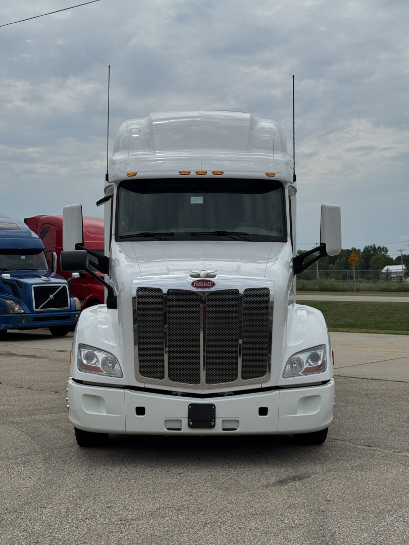Peterbilt 579 truck in white, front view showing large grille, dual exhaust stacks, and bumper; standard headlights and hood with Peterbilt emblem visible.