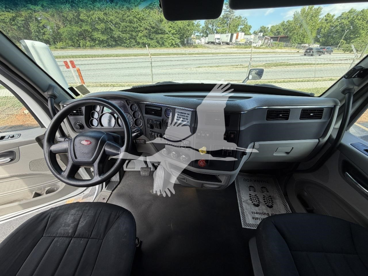 Peterbilt truck interior dashboard and steering wheel view with driver and passenger seats; dashboard instruments and center console visible.