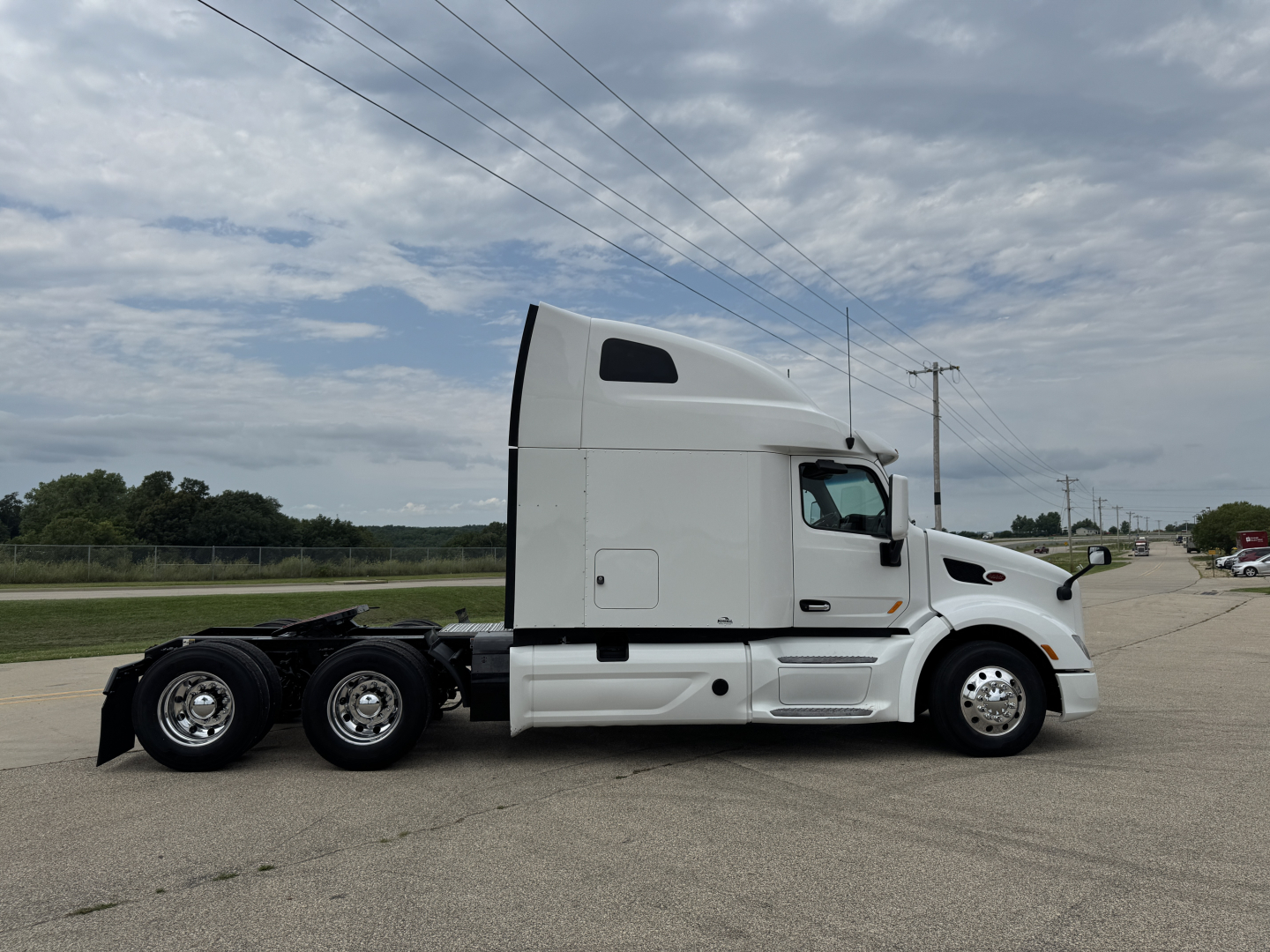 Peterbilt 579 tractor cab side view showing sleeper with white paint and dual rear axles.