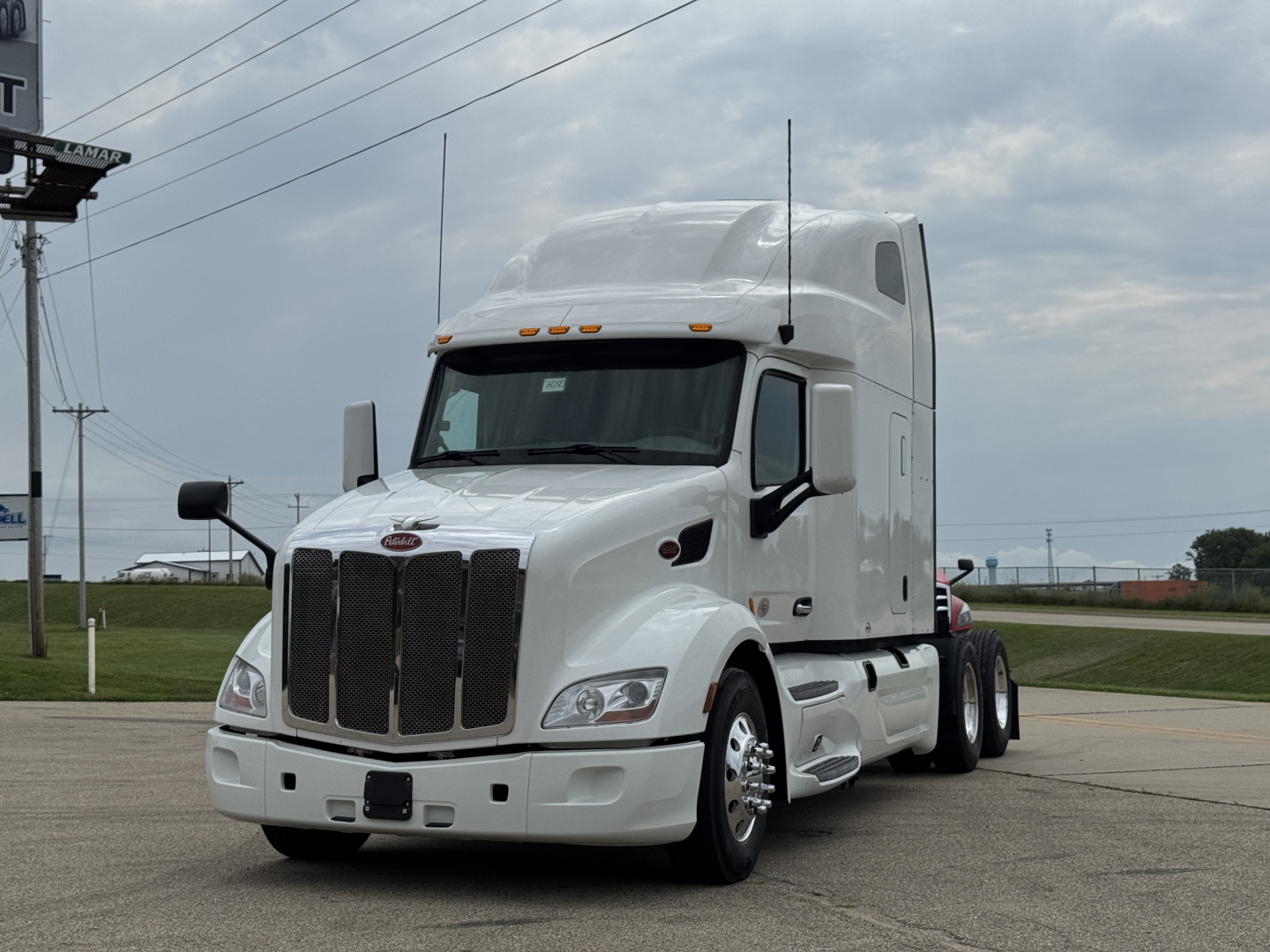 Peterbilt 579 conventional sleeper truck in white, front three-quarter view showing chrome grille, cab, and dual rear axles.