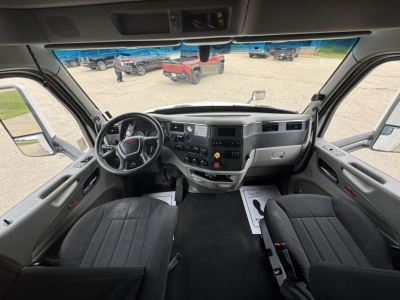 Cab interior of a 2022 Peterbilt 579 conventional sleeper showing dashboard with steering wheel, gauges, center console, and two front seats.