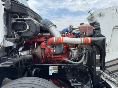 Peterbilt 579 engine bay with red engine and orange intake piping, various hoses and components visible.
