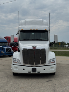 Peterbilt 579 truck in white, front view showing large grille, dual exhaust stacks, and bumper; standard headlights and hood with Peterbilt emblem visible.