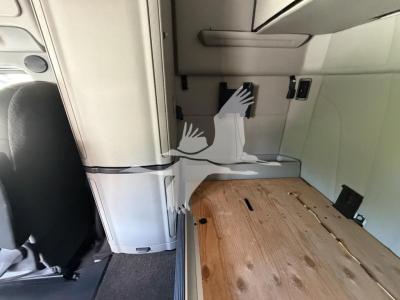 Cab interior of a Peterbilt 579 truck showing a wooden sleeper floor and wall panels; a vertical panel and utility outlets are visible.