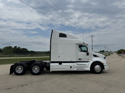 Peterbilt 579 tractor cab side view showing sleeper with white paint and dual rear axles.